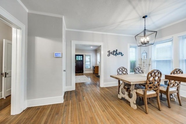 dining space featuring crown molding, baseboards, a notable chandelier, and light wood-style floors