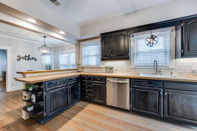kitchen featuring stainless steel dishwasher, a sink, visible vents, light wood-style floors, and backsplash