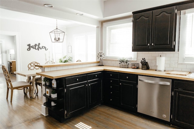 kitchen with pendant lighting, stainless steel dishwasher, wood-type flooring, and decorative backsplash