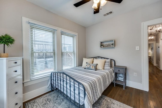 bedroom with baseboards, wood finished floors, visible vents, and ceiling fan with notable chandelier