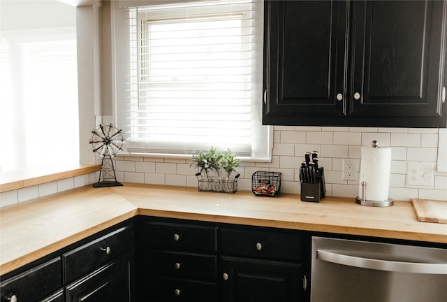 kitchen with butcher block counters, stainless steel dishwasher, and decorative backsplash