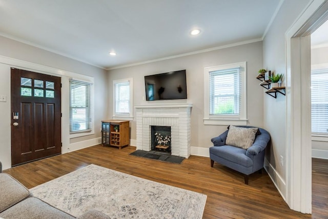 living area with baseboards, wood finished floors, and ornamental molding