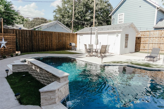 view of pool with grilling area, a patio, pool water feature, and a storage unit