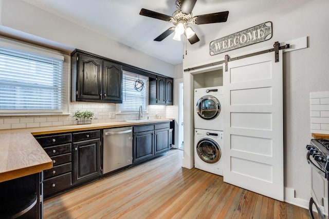 laundry room featuring a ceiling fan, a sink, light wood-type flooring, stacked washer and clothes dryer, and laundry area