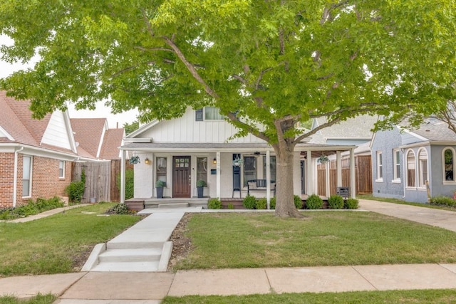 view of front of property with a front lawn, fence, a porch, and board and batten siding