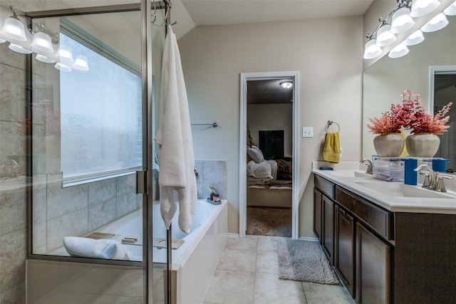 bathroom with a relaxing tiled tub, vanity, tile patterned flooring, and vaulted ceiling