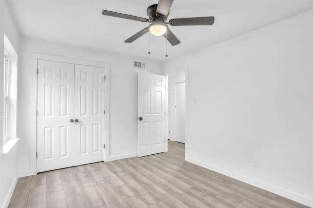 unfurnished bedroom featuring ceiling fan, light hardwood / wood-style floors, and a closet