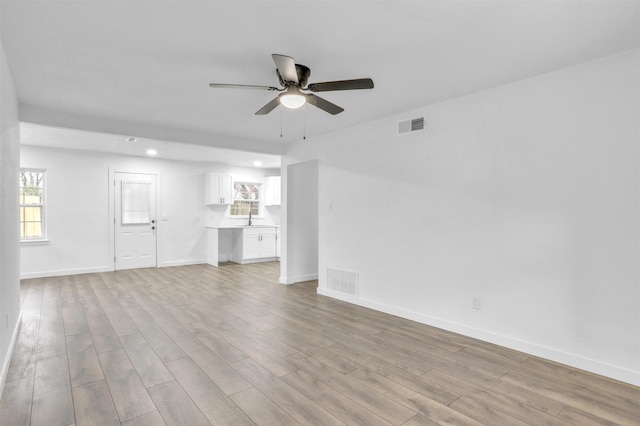 unfurnished living room featuring ceiling fan and light wood-type flooring