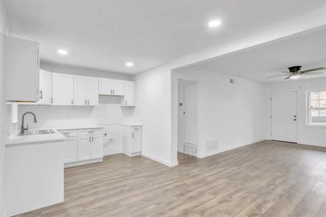 kitchen with ceiling fan, sink, white cabinets, and light hardwood / wood-style floors