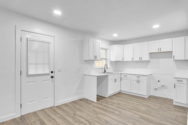 kitchen featuring sink, white cabinets, backsplash, and light hardwood / wood-style flooring