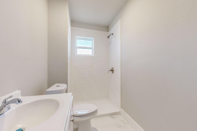 bathroom with vanity, toilet, and tiled shower