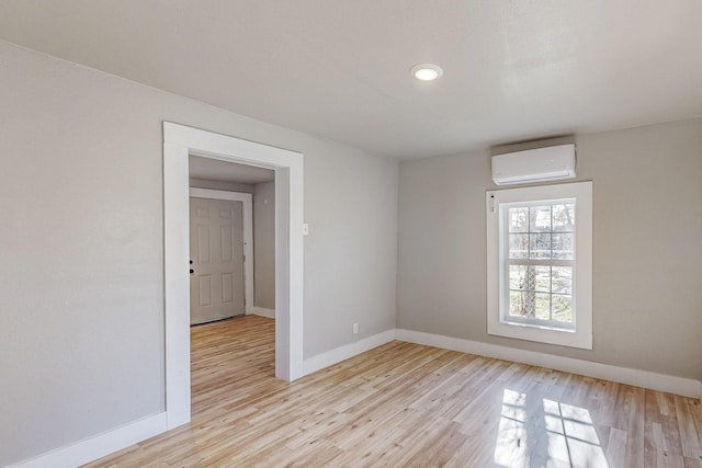 spare room with light wood-type flooring and an AC wall unit