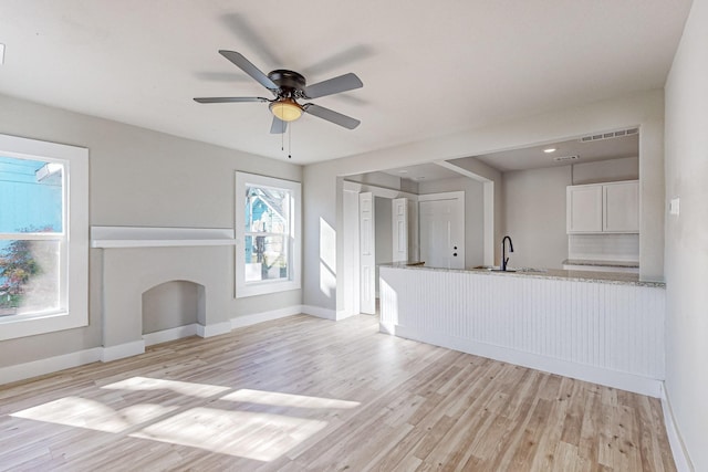 unfurnished living room featuring sink, ceiling fan, and light wood-type flooring