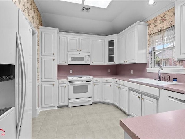 kitchen with sink, white appliances, white cabinets, and light tile patterned flooring