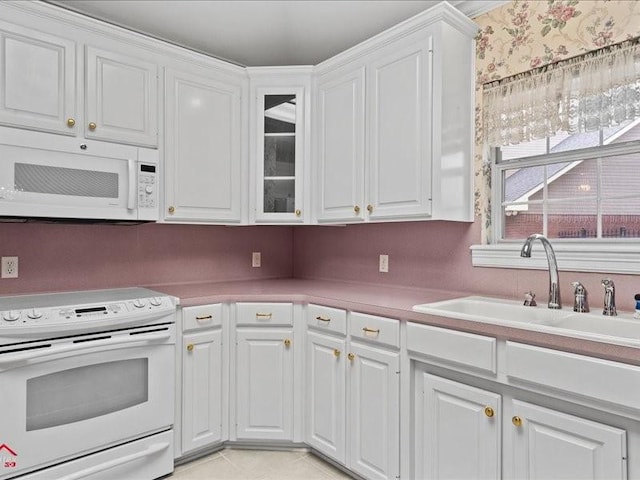 kitchen featuring white cabinetry, sink, light tile patterned flooring, and white appliances