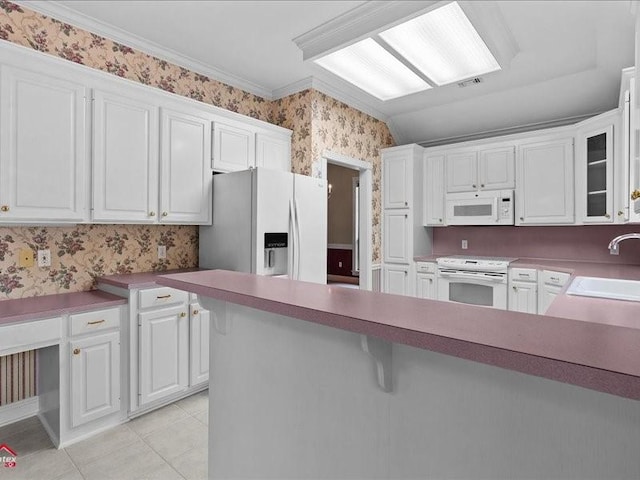 kitchen with light tile patterned flooring, white cabinetry, sink, crown molding, and white appliances