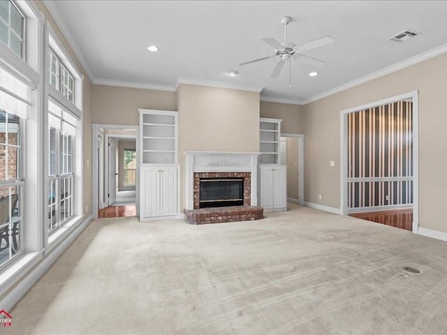 unfurnished living room with ceiling fan, ornamental molding, a fireplace, and light carpet