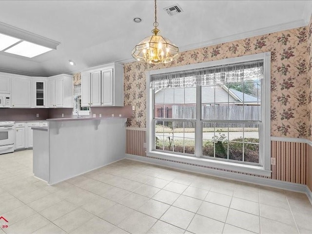 kitchen with hanging light fixtures, a kitchen breakfast bar, kitchen peninsula, white appliances, and white cabinets