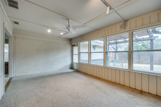 unfurnished sunroom with rail lighting and ceiling fan