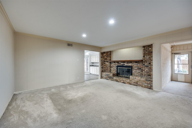 unfurnished living room with a brick fireplace, crown molding, and carpet