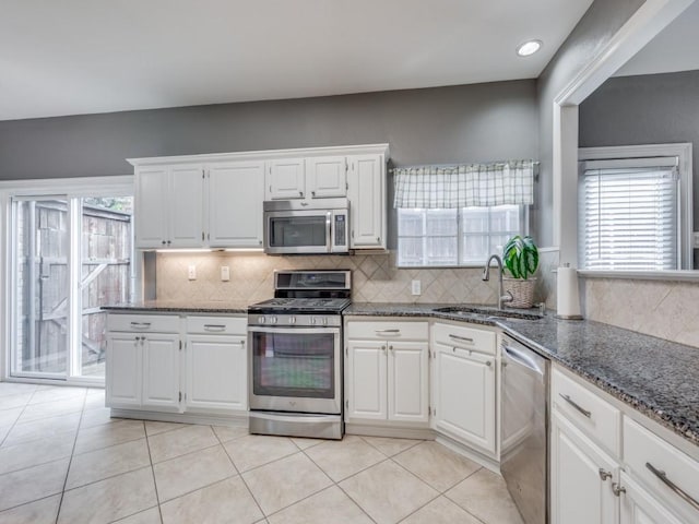 kitchen featuring dark stone countertops, stainless steel appliances, sink, and white cabinets