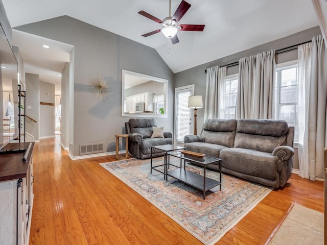 living room with ceiling fan, lofted ceiling, and light hardwood / wood-style floors