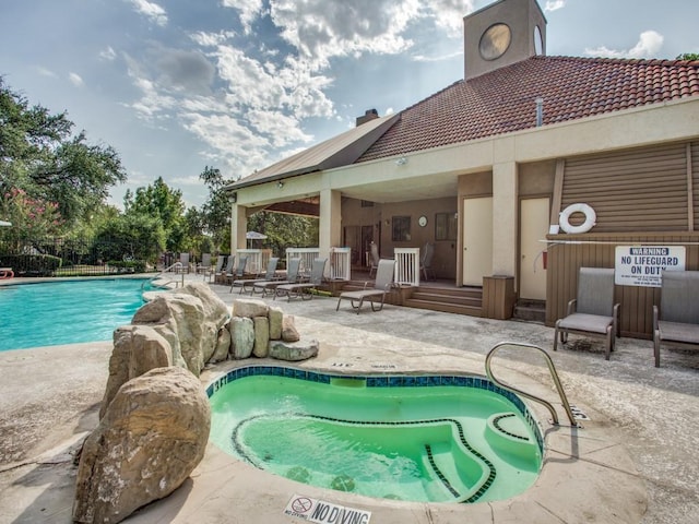 view of swimming pool featuring a community hot tub and a patio area