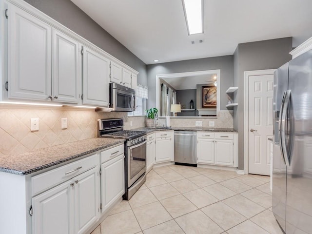 kitchen featuring tasteful backsplash, appliances with stainless steel finishes, light tile patterned floors, and white cabinets