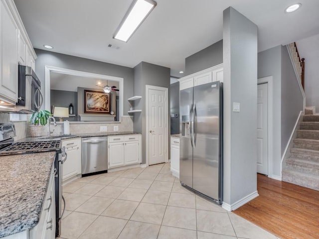 kitchen with light tile patterned flooring, stainless steel appliances, decorative backsplash, and white cabinets