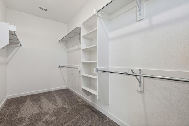 walk in closet with dark carpet