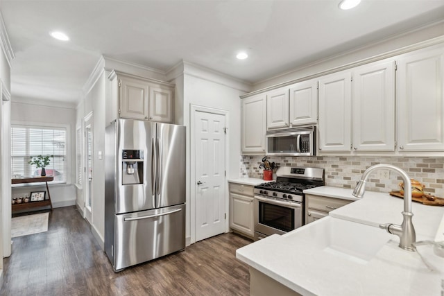 kitchen with white cabinetry, ornamental molding, appliances with stainless steel finishes, dark hardwood / wood-style floors, and backsplash