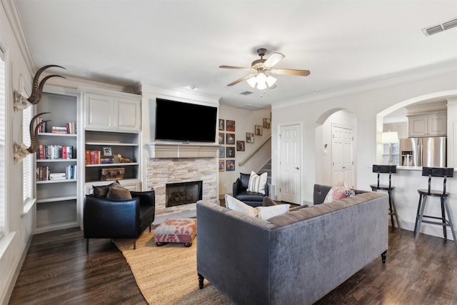 living room with crown molding, a fireplace, dark hardwood / wood-style floors, and ceiling fan