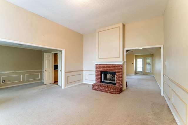 unfurnished living room featuring light carpet, a decorative wall, and a fireplace