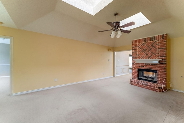 unfurnished living room with carpet, a fireplace, a ceiling fan, vaulted ceiling with skylight, and baseboards