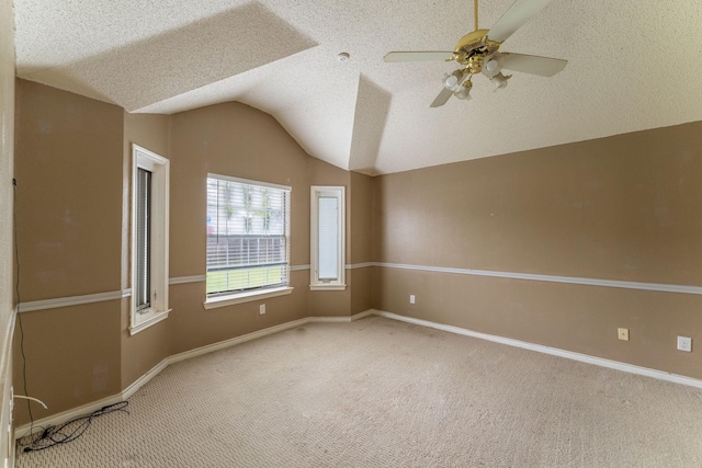 carpeted empty room featuring lofted ceiling, ceiling fan, baseboards, and a textured ceiling