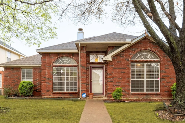 ranch-style house featuring brick siding, a shingled roof, and a front yard