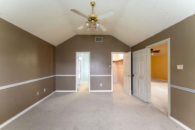 unfurnished bedroom with a textured ceiling, visible vents, vaulted ceiling, a walk in closet, and ensuite bath