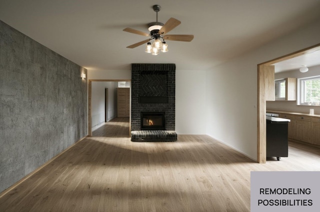 unfurnished living room with light wood-type flooring, a brick fireplace, and ceiling fan