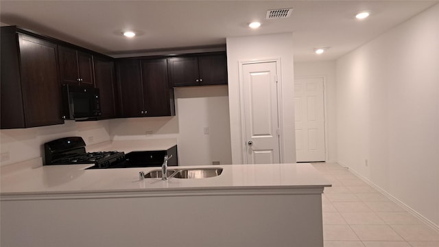 kitchen with sink, kitchen peninsula, dark brown cabinetry, and black appliances