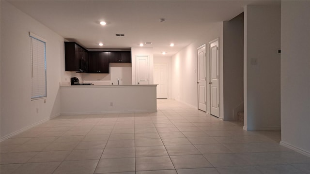 kitchen featuring dark brown cabinetry, kitchen peninsula, sink, and light tile patterned floors