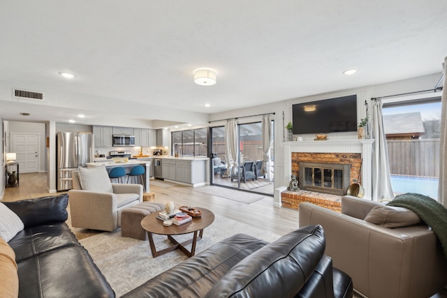 living room featuring a wealth of natural light, a fireplace, and light wood-type flooring