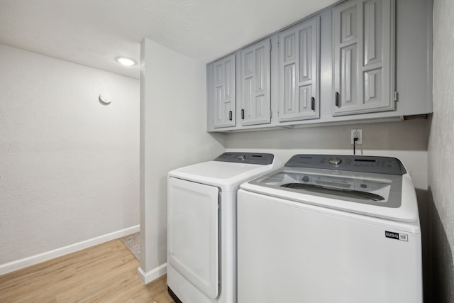 laundry room with cabinets, light hardwood / wood-style floors, and washing machine and dryer