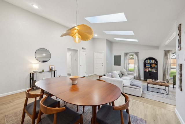 dining room featuring lofted ceiling with skylight and light wood-type flooring