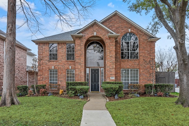 traditional home featuring brick siding, a front lawn, and roof with shingles