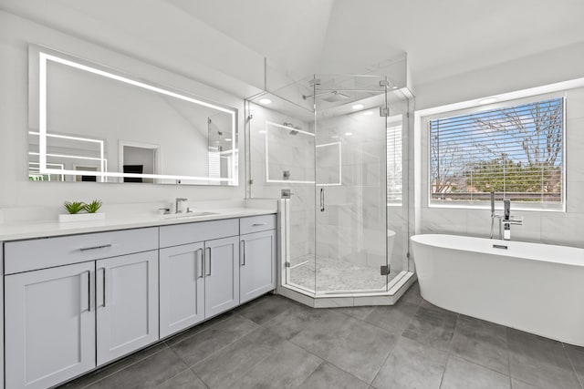 full bath with lofted ceiling, vanity, a freestanding bath, tile patterned floors, and a stall shower