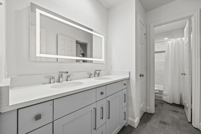 full bathroom featuring double vanity, a shower with shower curtain, a sink, and toilet