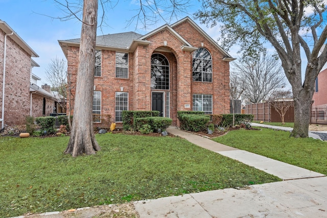 colonial inspired home with fence, a front lawn, and brick siding