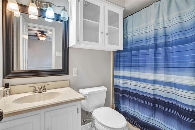 bathroom featuring walk in shower, ceiling fan, vanity, and toilet