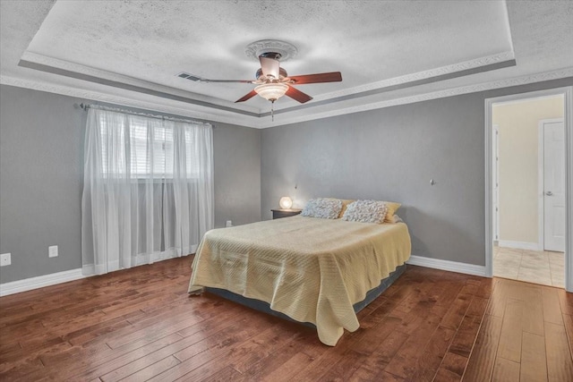 bedroom featuring dark hardwood / wood-style floors, a raised ceiling, and a textured ceiling