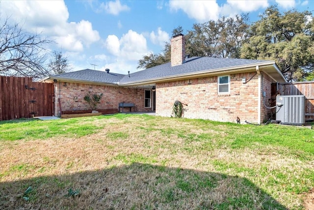 back of house featuring central AC unit and a lawn